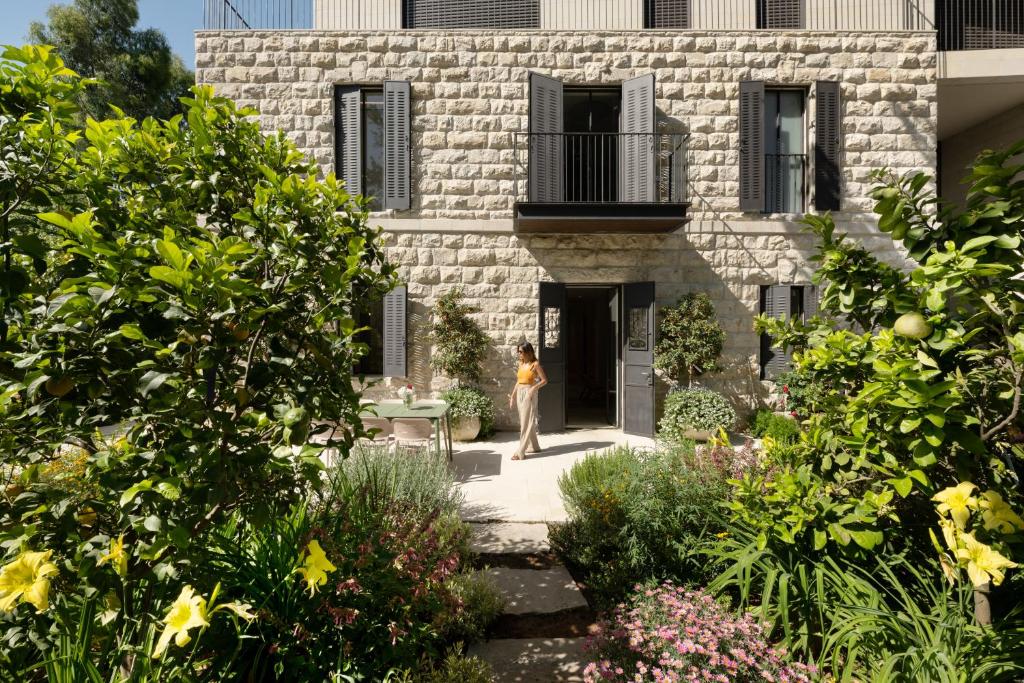 a woman standing in front of a stone building at THE Y HOUSE in Jerusalem