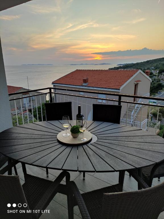 a wooden table with wine glasses on a balcony at Apartman Vesa in Dolac