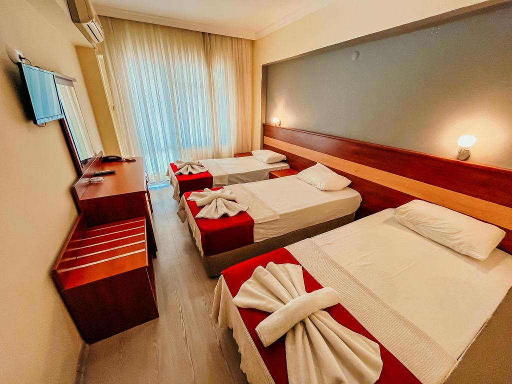 ディディムにあるHotel First Class Didimのベッド3台と窓が備わるホテルルームです。