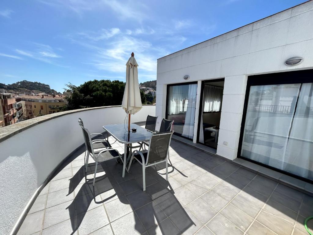 balkon ze stołem, krzesłami i parasolem w obiekcie Apartamentos TDM w Tossa de Mar