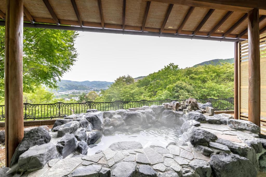a large rock pool in a backyard with a waterfall at 天然温泉&絶景露天風呂付き貸切宿のんびり一非日常空間を愉しむ一10人でも広々 in Izu