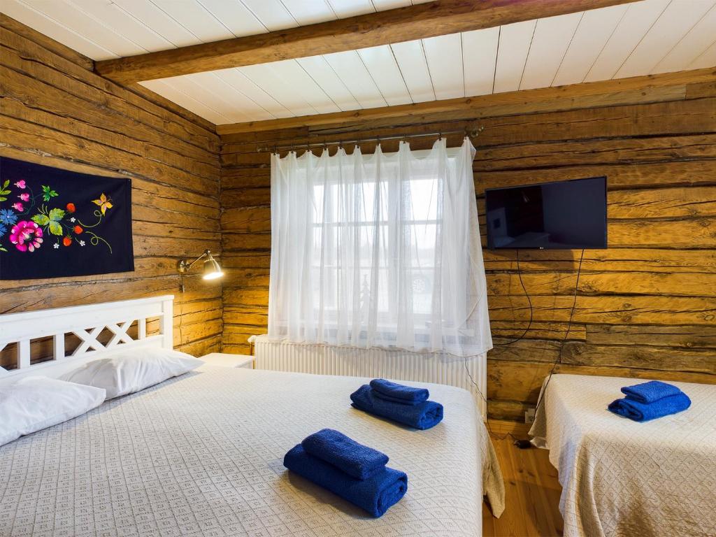 two beds in a room with wooden walls at Pädaste Välja Apartments in Pädaste