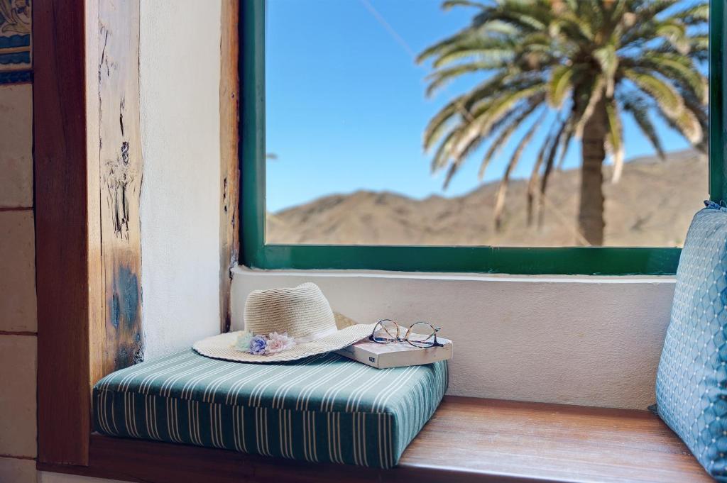 a hat and glasses sitting on a window seat at Rosa del Negro in Alojera