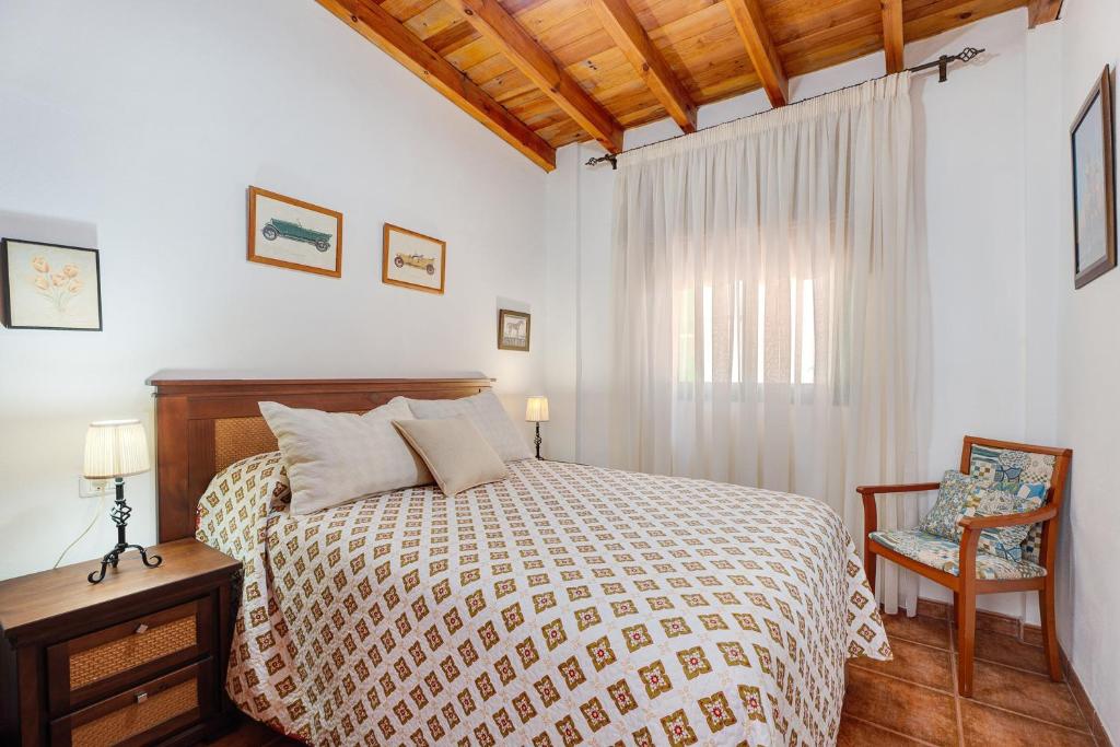 a bedroom with a bed and a chair and a window at Rosa del Negro in Alojera