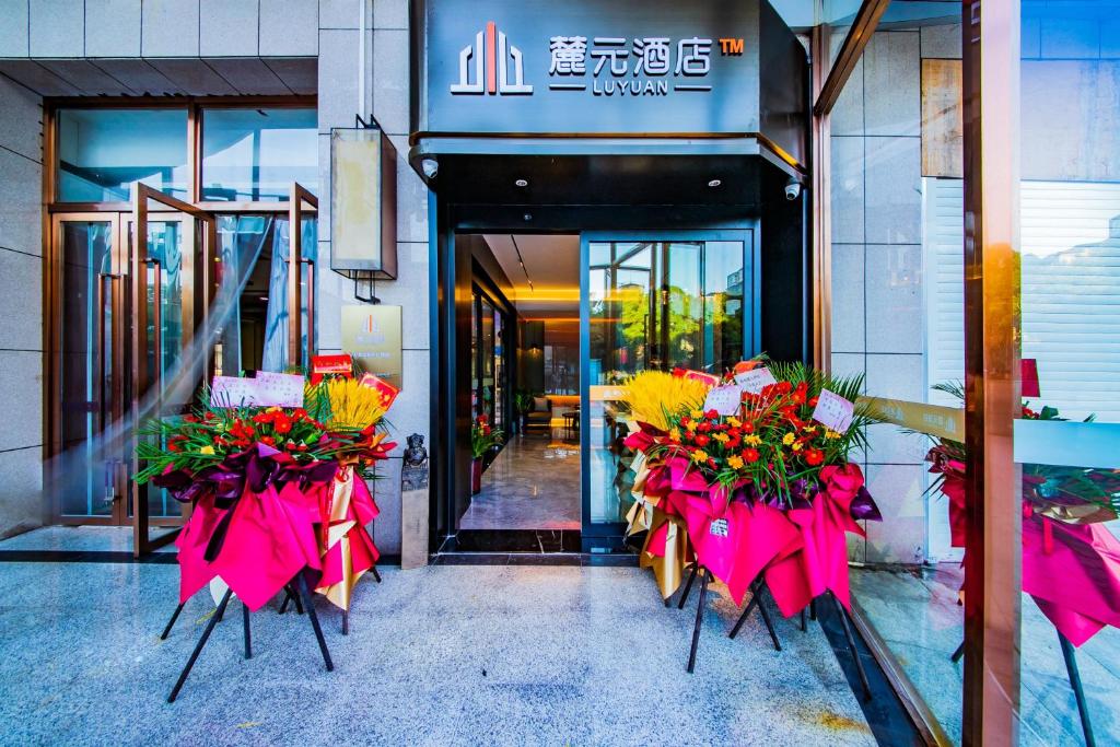 Luyuan Hotel, Changsha Railway Station Metro Station في تشانغشا: حفنة من الزهور أمام مبنى