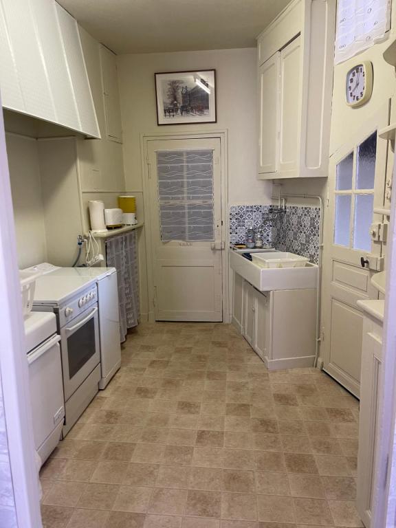 una pequeña cocina con electrodomésticos blancos y una puerta en French Holiday Accommodation, en Bort-les-Orgues