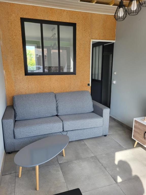 sala de estar con sofá azul y mesa en Studio proche gare TGV Haute Picardie en Dompierre-Becquincourt