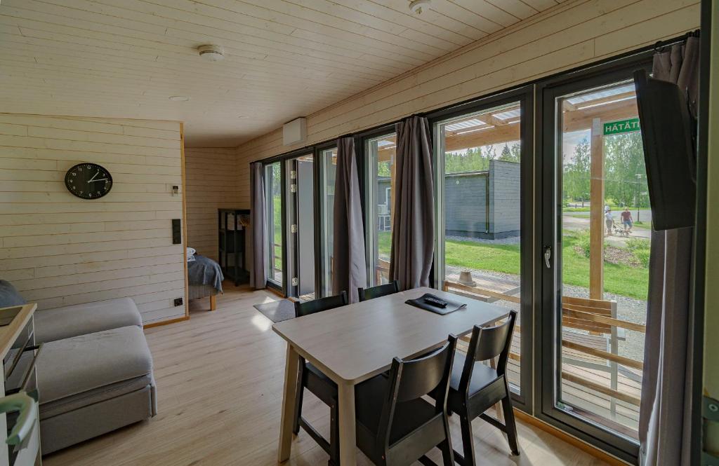 a living room with a table and chairs and windows at Rauhalahti Holiday Homes in Kuopio