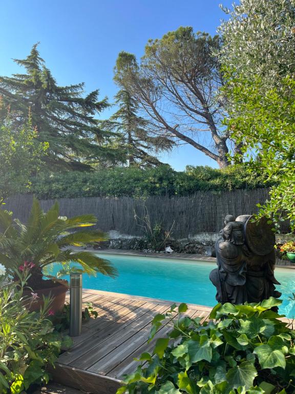 un jardin avec une statue à côté d'une piscine dans l'établissement Maison 3 chambres avec piscine dans un jardin luxuriant, à Puget-sur Argens