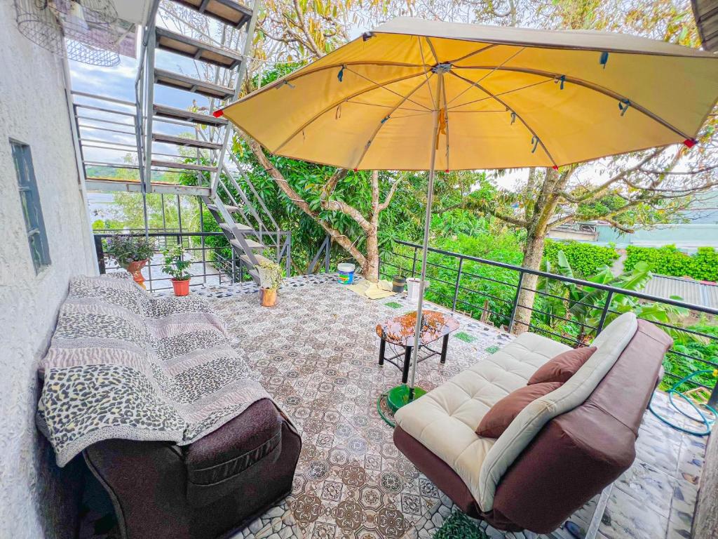 een patio met een bank en een parasol bij Gió Homestay - Pleiku in Pleiku