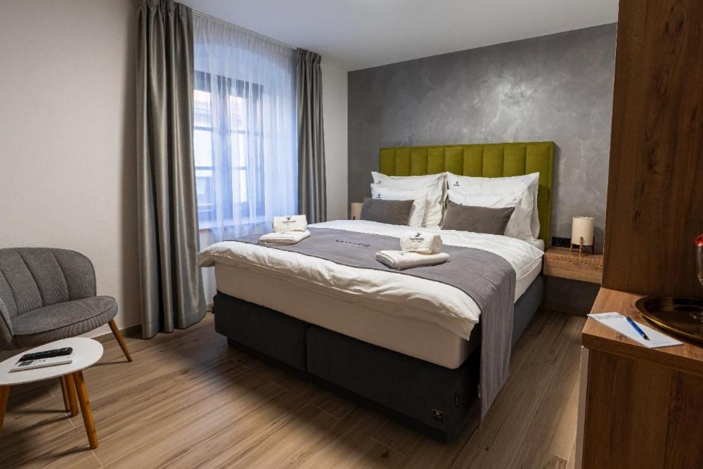 een slaapkamer met een groot bed en een stoel bij Penzion Monner in Mikulov