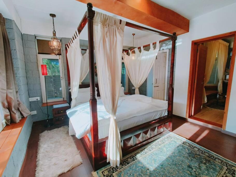 a bedroom with a canopy bed and a mirror at Eco Farmstay Cottages #1 in Dharamshala