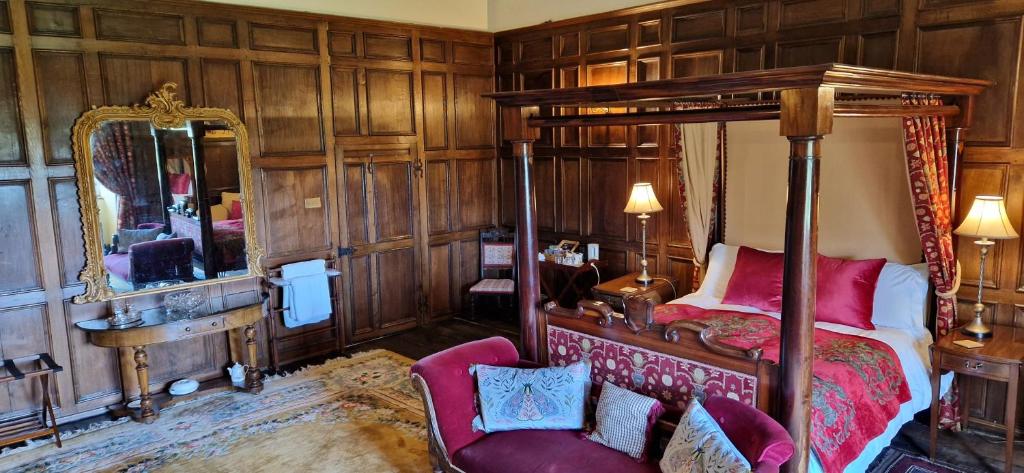 a bedroom with a canopy bed and a mirror at Braithwaite Hall Bed & Breakfast in Middleham