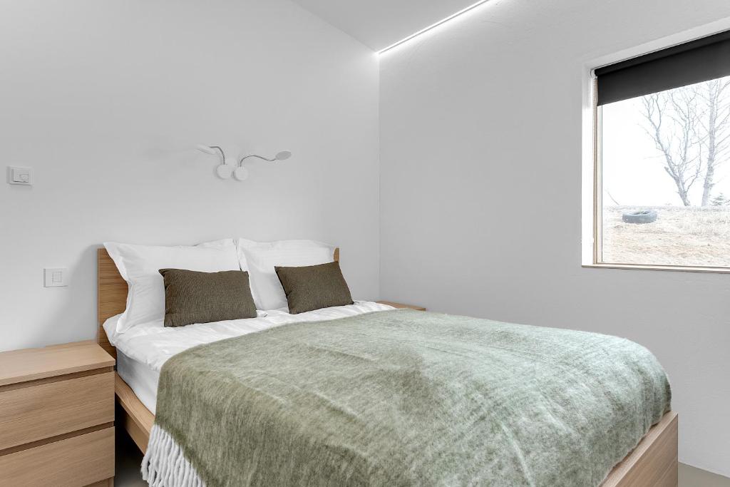 een witte slaapkamer met een bed en een raam bij Klettar - The Old Hatchery Iceland in Fludir