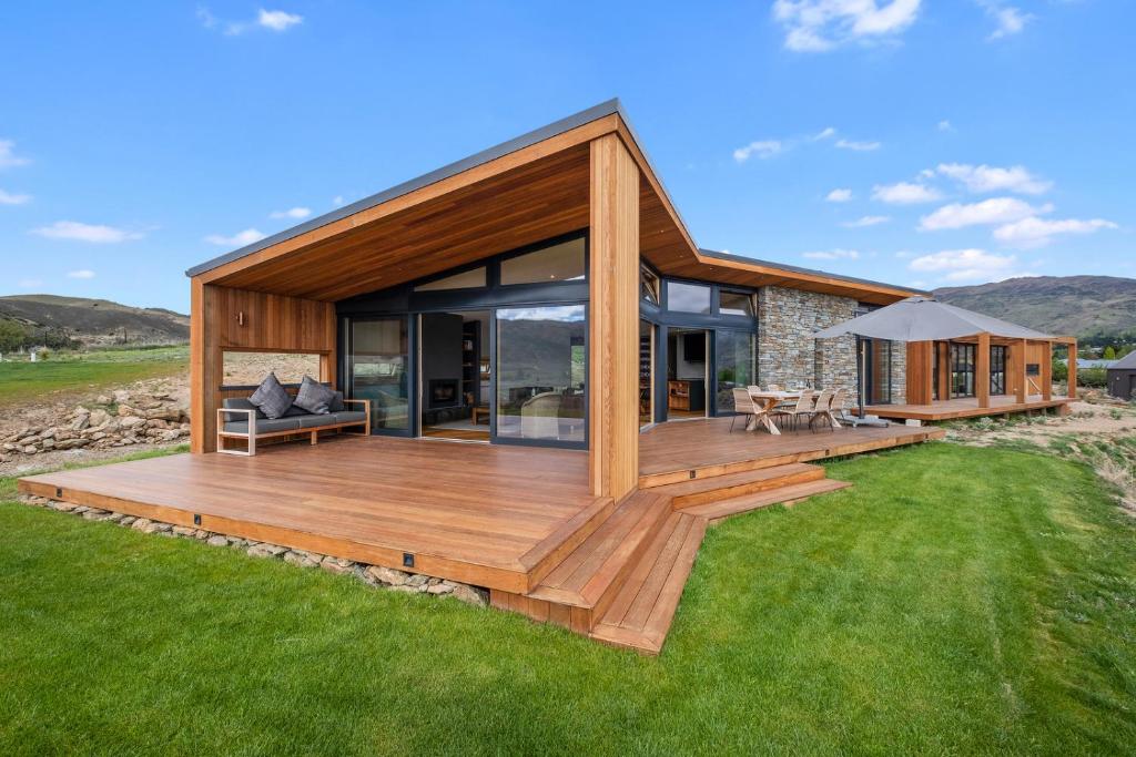 a house with a large wooden deck on a lawn at Vino and Views - Bannockburn Holiday Home in Cromwell
