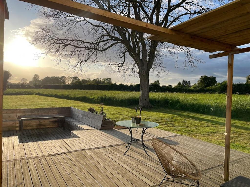 a patio with a table and chairs and a tree at "Le Val des Prés" Atypique, Chambres spacieuses dans ancienne usine 