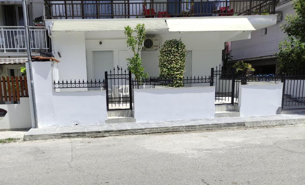 a white house with a black fence in front of it at White coral 2 in Paralia Katerinis
