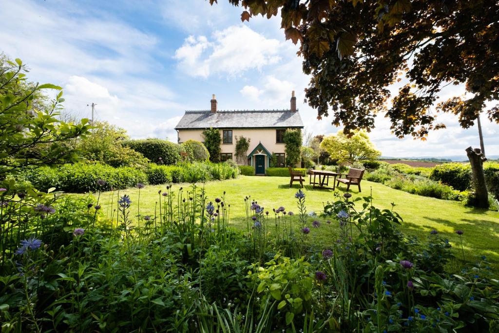 a house in the middle of a field with flowers at Wye Valley Holiday Cottage - Field Cottage in Peterstow