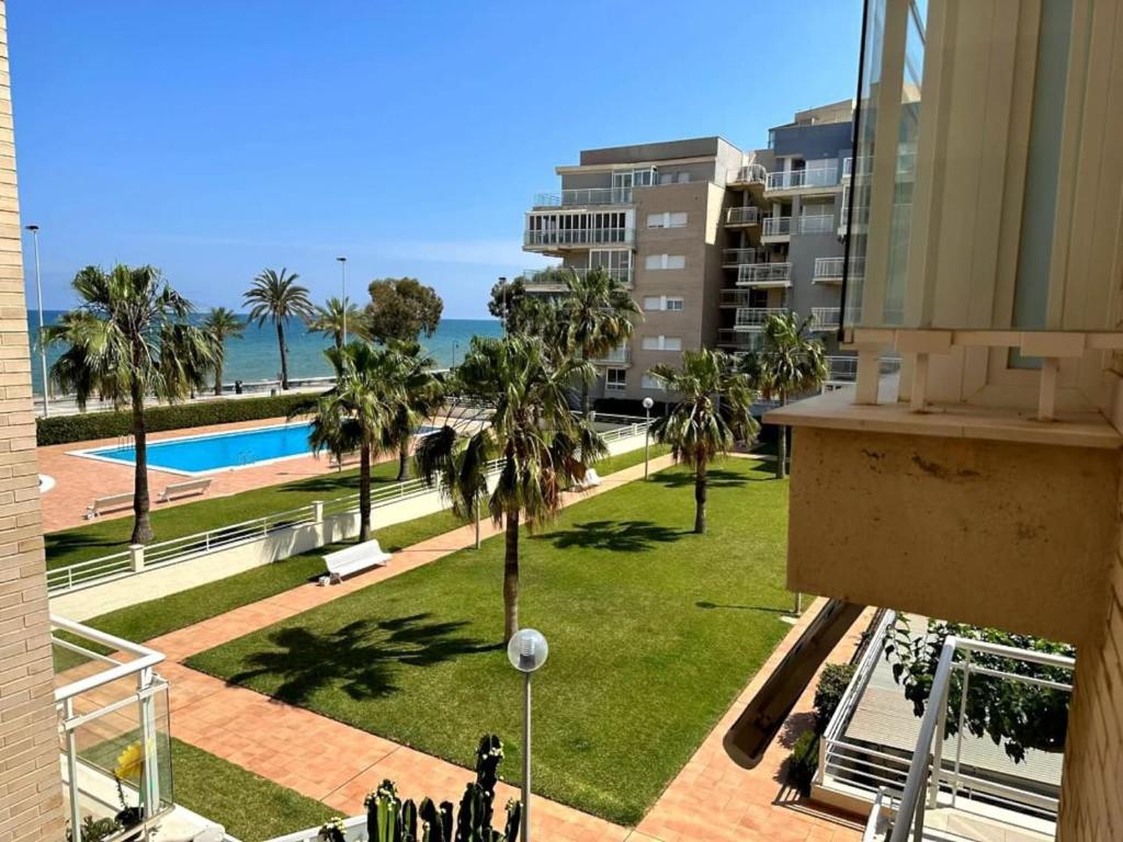 uitzicht op een park met palmbomen en de oceaan bij Seaside Apartment Retreat in Benicàssim