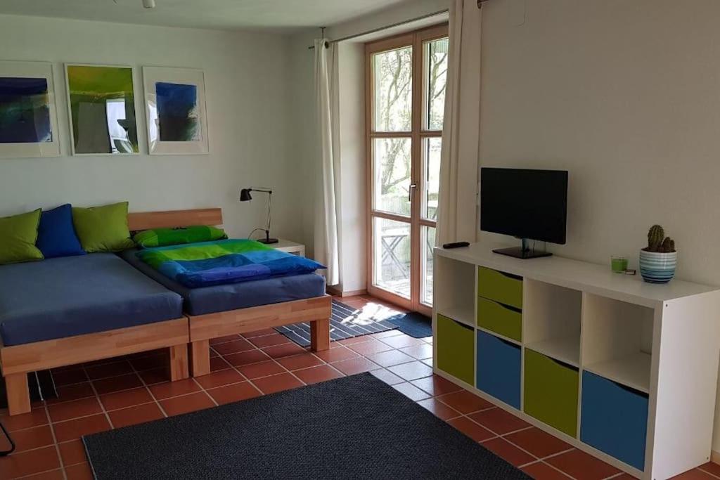 a living room with a blue couch and a tv at Gemütliche Wohnung mit Terrasse in der Nähe vom Bodensee in Tettnang