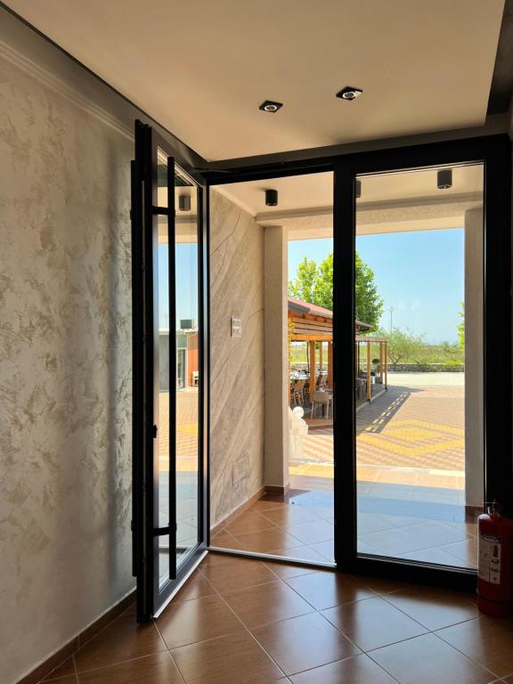 une porte en verre ouverte avec vue sur un bâtiment dans l'établissement Kamberi Hotel & Apartments, à Velipojë