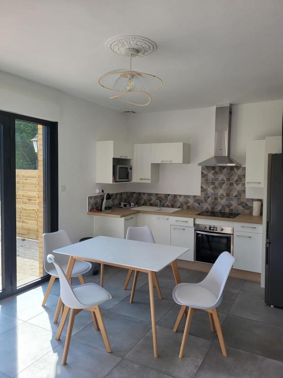 une cuisine avec une table et des chaises dans une pièce dans l'établissement GITE 4-6 Personnes proche gare TGV Haute Picardie, à Dompierre-Becquincourt