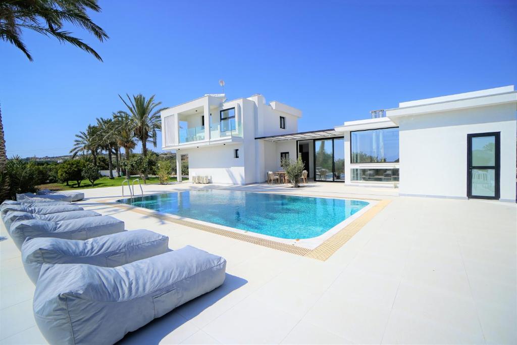 派亞的住宿－Luxury 4 Bedroom Oasis Villa，一座大型白色房屋,设有游泳池和躺椅