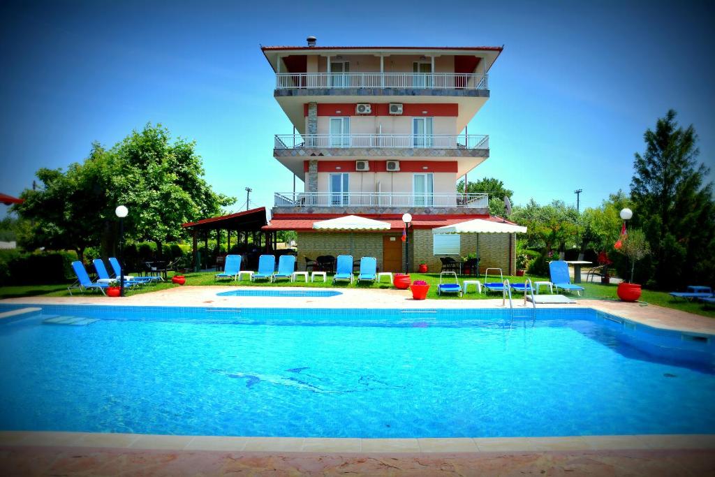 a building with a swimming pool in front of a building at Denis Hotel and Bungalows in Korinós