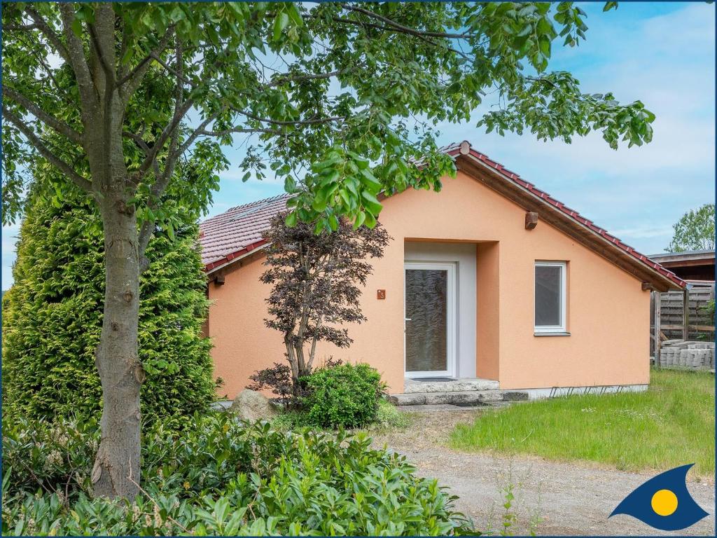 una pequeña casa con un árbol delante en Ferienhaus Pauline, en Trassenheide