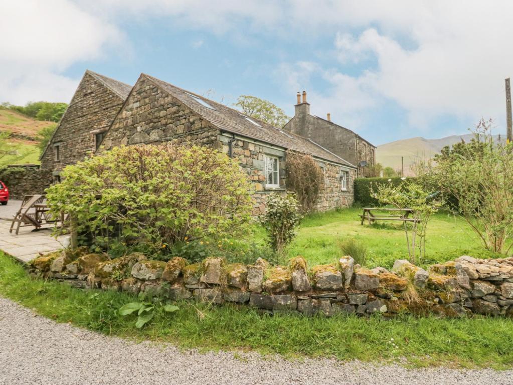 ein altes Steinhaus mit einer Steinmauer in der Unterkunft Shundraw Cottage in Keswick