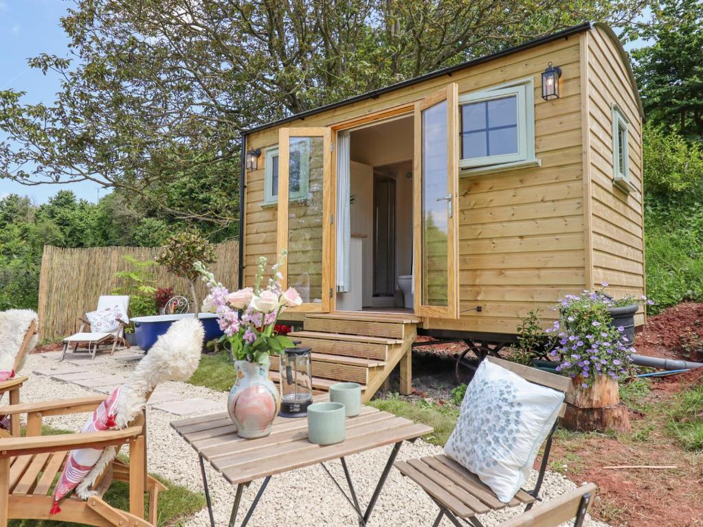a tiny house in a yard with a table and chairs at Coombe Valley Shepherd's Hut in Shaldon