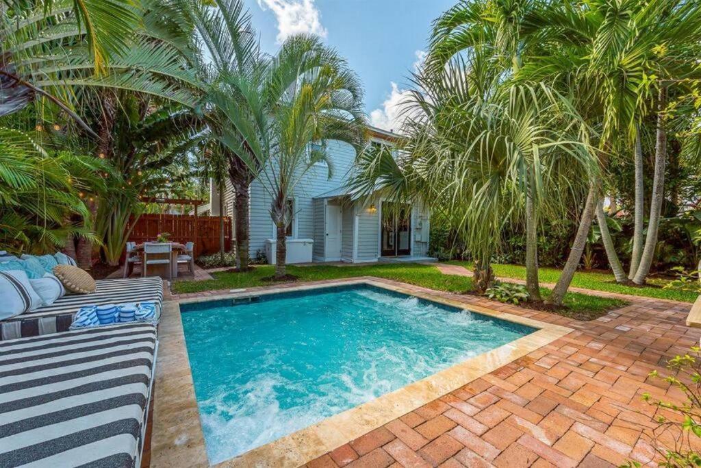 a swimming pool in front of a house with palm trees at Tropical Estate w/ Guesthouse & Pool. Sleeps 8! in West Palm Beach