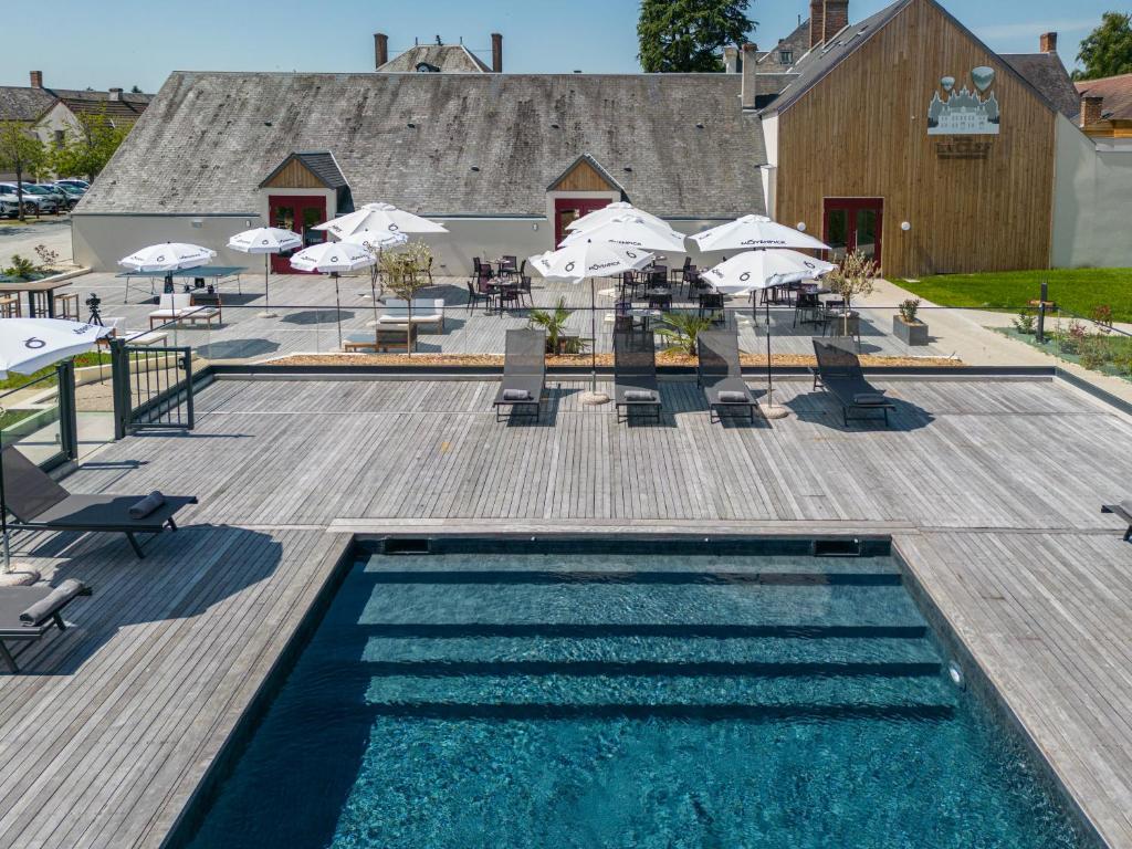 una piscina con sombrillas, mesas y sillas en La Clef des Châteaux, en Maslives