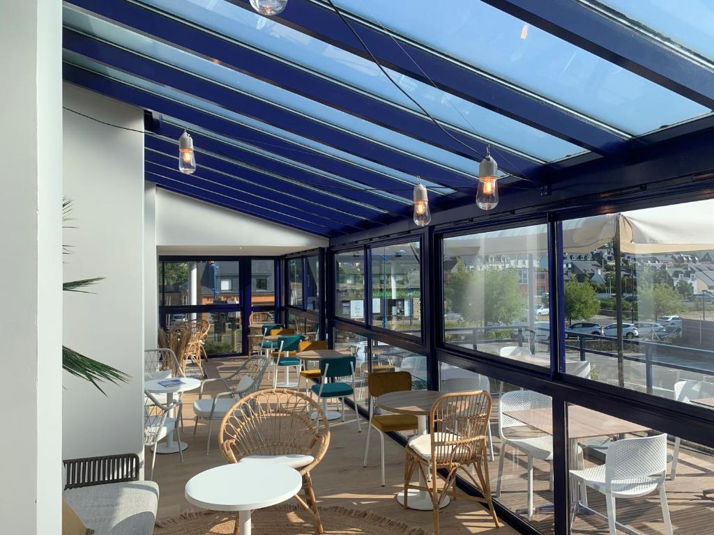 un restaurante con techos azules, mesas y sillas en L'Escale Marine, The Originals Relais, en Crozon