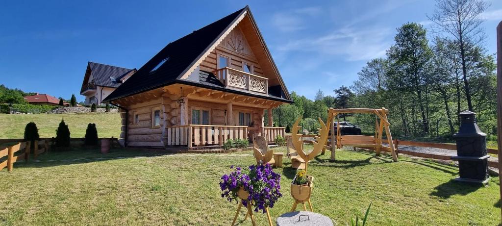 a small log cabin with a playground in the yard at Góralski Dom z pięknymi widokami na góry in Sosnówka