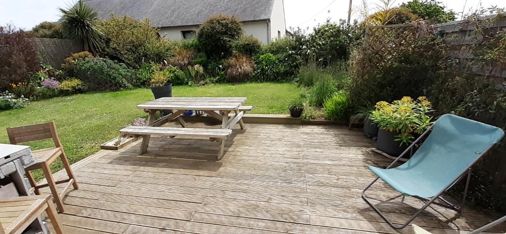 um pátio de madeira com uma mesa de piquenique e uma cadeira azul em Maison moderne mitoyenne exposée plein sud avec terrasse em Trégastel