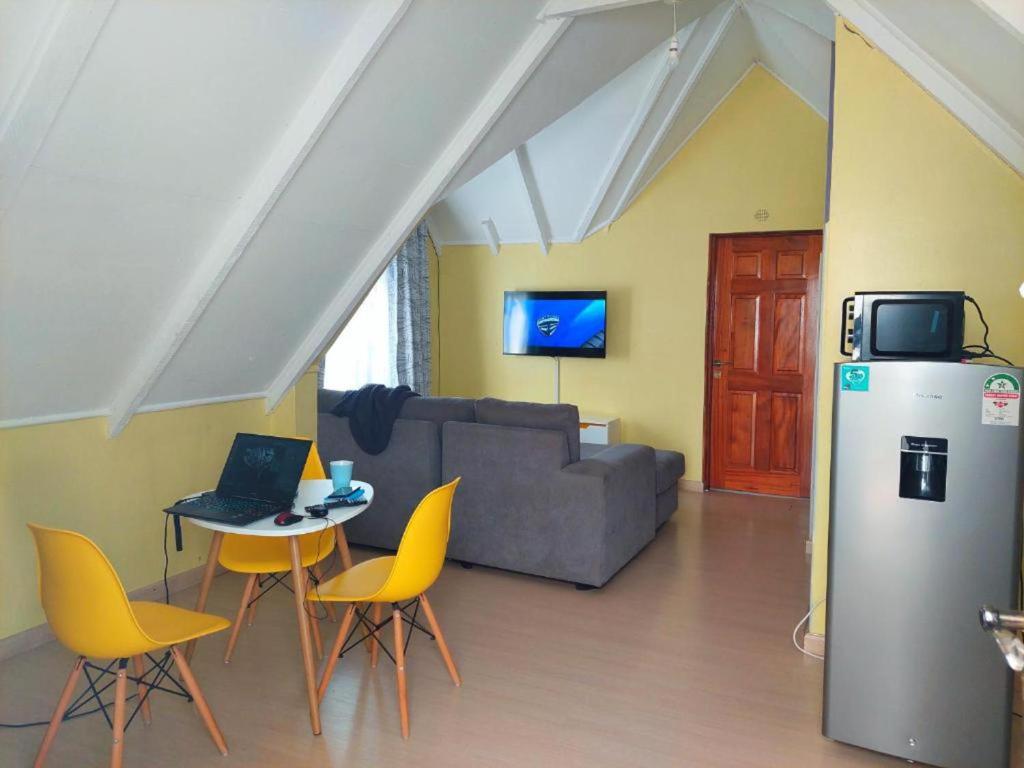 a living room with a couch and a table and yellow chairs at Charming 1-Bed Penthouse in Karen Nairobi in Nairobi