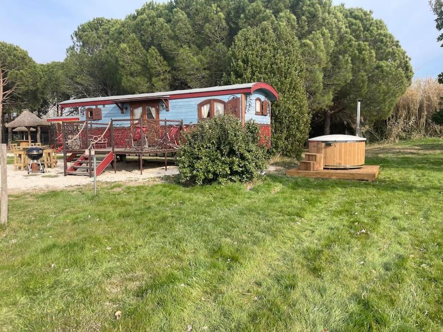a red train car sitting in a grass field at Le Pont Rouge Roulotte in Sylvéréal
