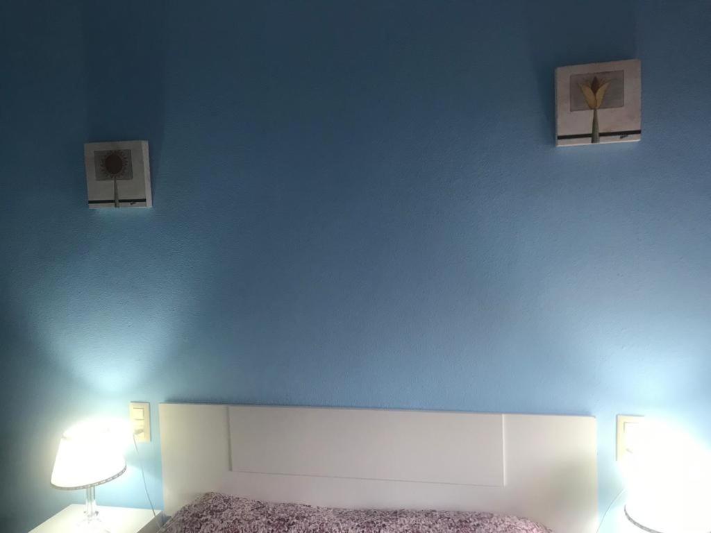 - une chambre dotée d'un mur bleu avec un lit et deux lampes dans l'établissement Apartamento avenida, à Elche de la Sierra