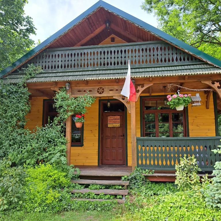 Ce chalet en bois dispose d'une véranda et d'une porte. dans l'établissement Domek Myśliwski z sauną, 