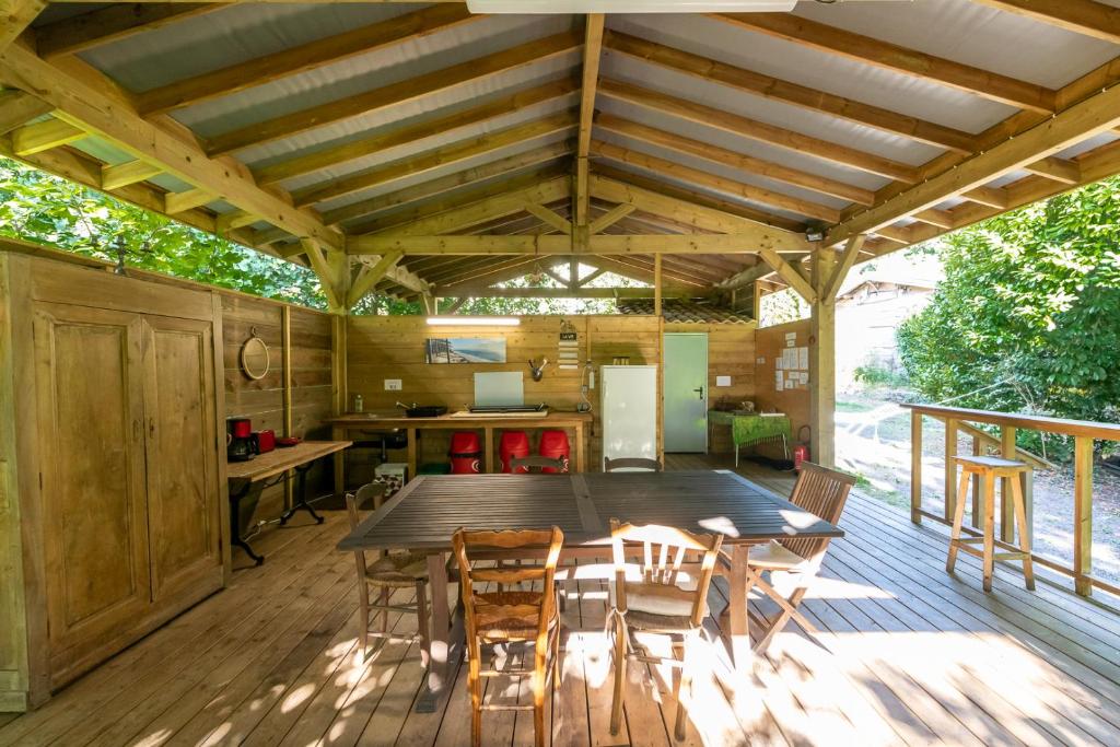 a wooden patio with a table and chairs on a deck at Le tipi Arc-en-ciel au bord de la rivière in Mios