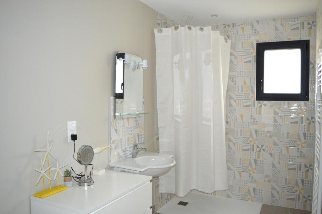 a bathroom with a sink and a shower curtain at La Fossette, maison neuve au coeur des plages in Asnelles