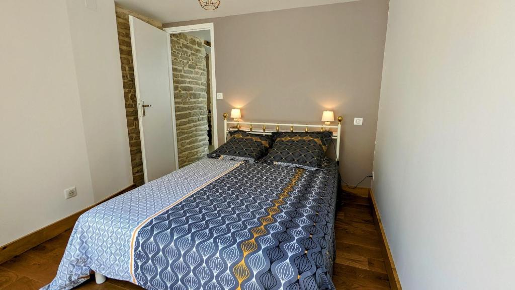 a bedroom with a bed with a blue comforter and pillows at Le Cocon des Hautes-Côtes in Fussey