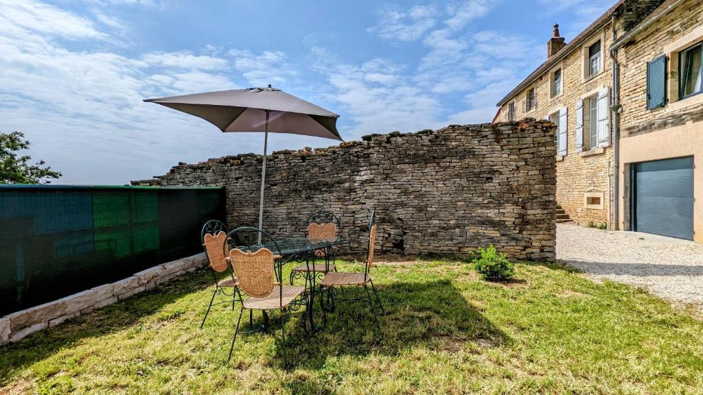 einen Tisch und Stühle mit Sonnenschirm im Hof in der Unterkunft Le Cocon des Hautes-Côtes in Fussey