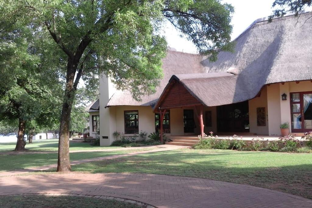 a house with a thatched roof and a tree at Gentleman's Estate on the Vaal River in Vanderbijlpark