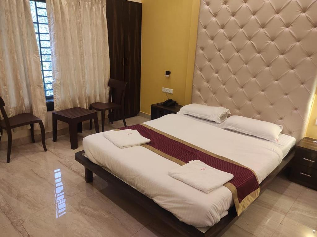 a bedroom with a large bed with a large headboard at Hotel Deepak Executive, Ganpatipule in Ganpatipule