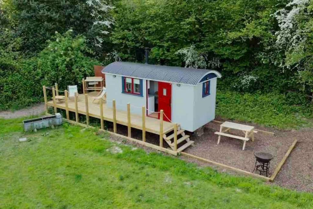 una pequeña casa con porche y banco en Cleo’s Hut, en Cowfold