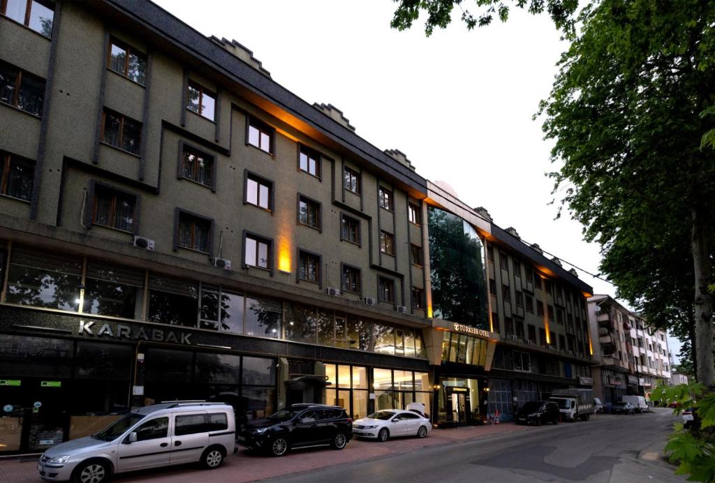 un grande edificio con macchine parcheggiate di fronte di Türkler Suite Hotel a Trabzon
