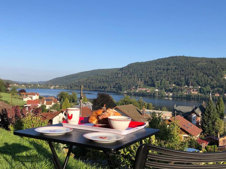 - une table avec de la nourriture et une vue sur le lac dans l'établissement Appartement cosy - grande terrasse pleine vue lac, à Gérardmer