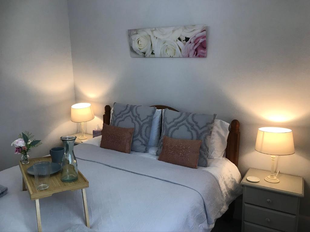 a bedroom with a white bed with two lamps at The Cornish Peak by StayStaycations in Camelford